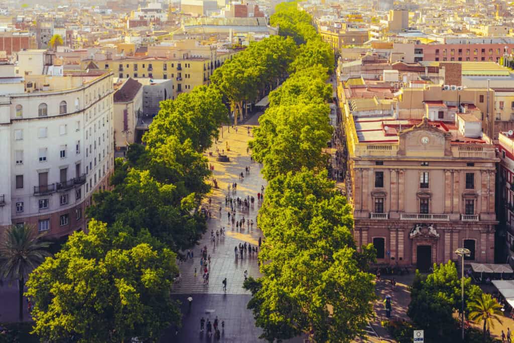 Aerial view of Mitte Berlin with lush green trees lining a busy pedestrian street and historic archi.