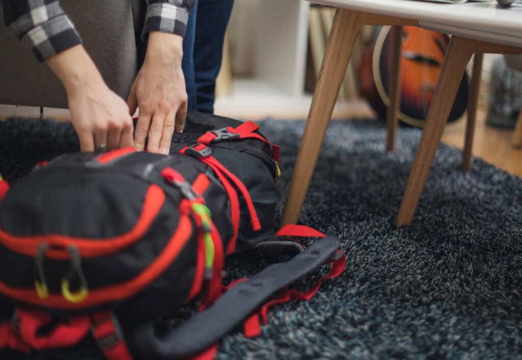Brightly coloured backpack on a black carpet in a hostel room.
