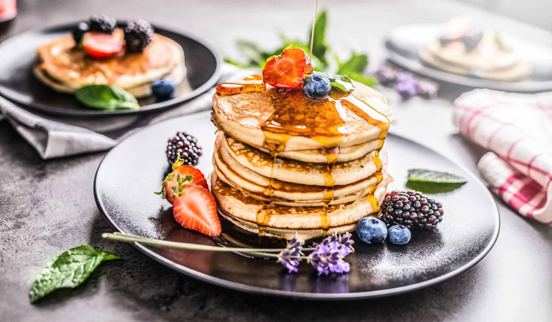 A stack of fluffy pancakes with berries and syrup, perfect for breakfast at St Christopher’s Berlin.