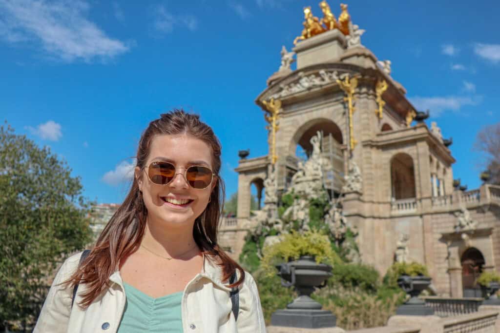 Young woman smiling in front of historic Mitte landmark, Berlin, on a sunny day.
