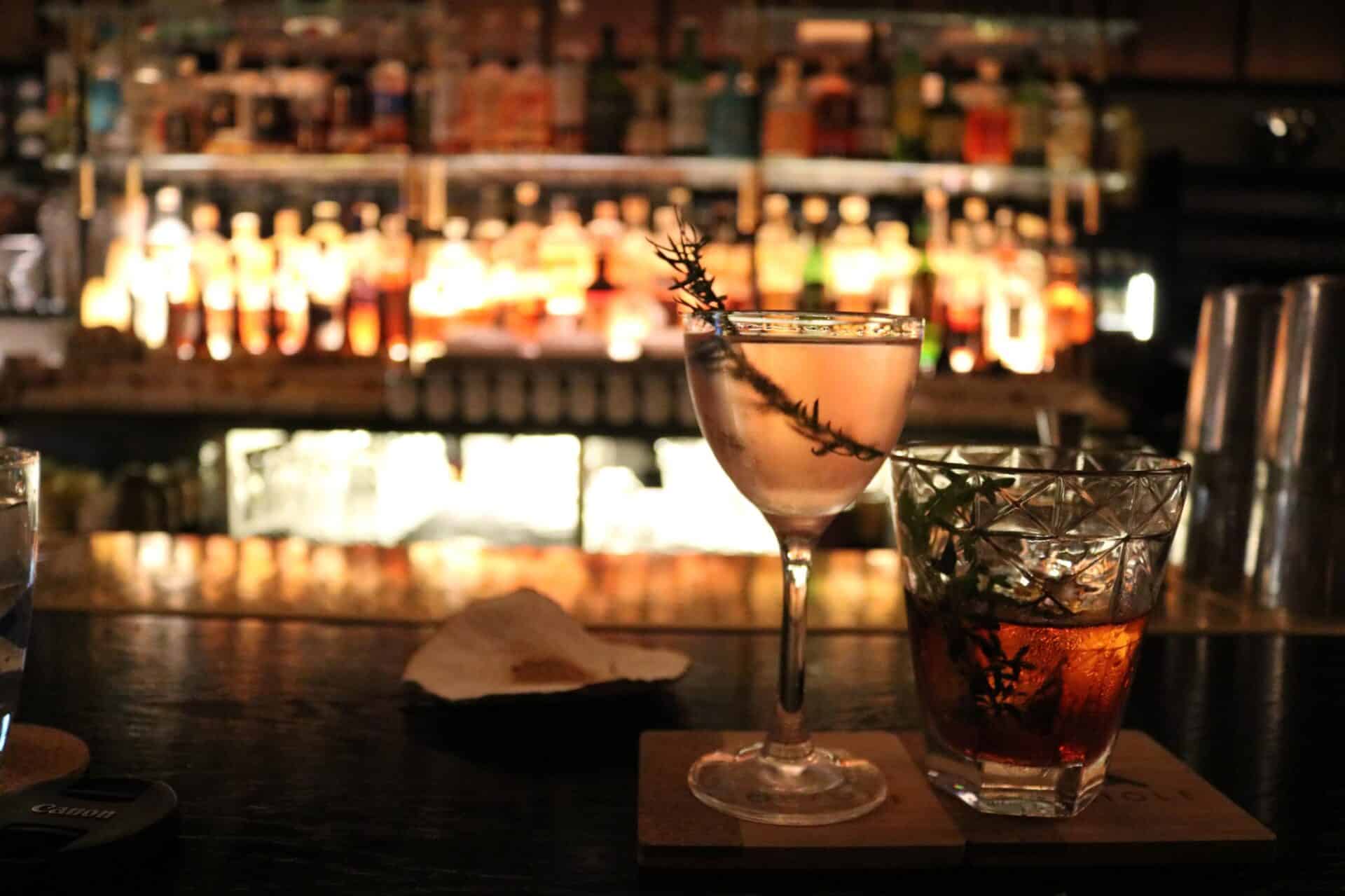 A colourful cocktail and a glass of whiskey on a bar counter at St Christopher’s Berlin - Mitte.