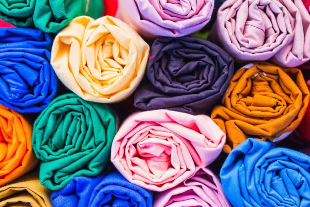 Brightly coloured rolled fabric towels in various shades, arranged in a close-up.