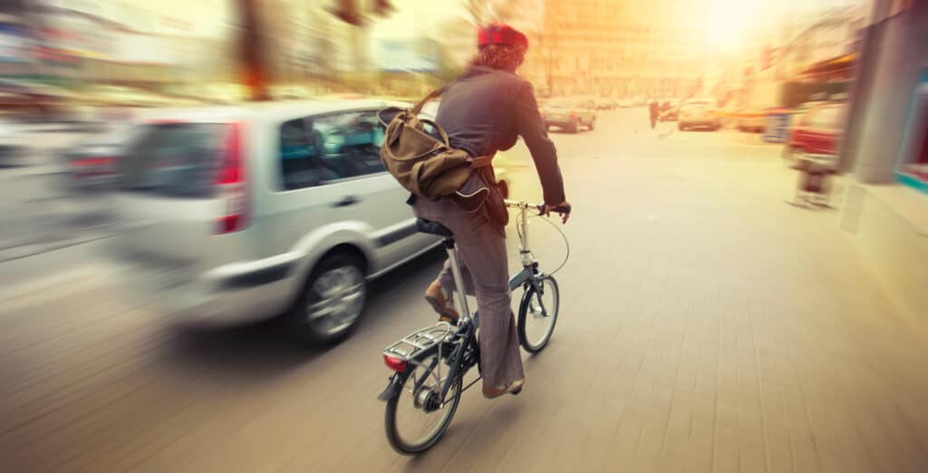 Cyclist riding a bike through Mitte, Berlin, with cars and city streets in the background.