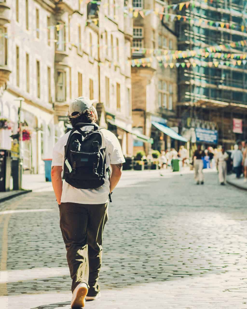 Person walking in a city street with backpack, historic buildings in the background.