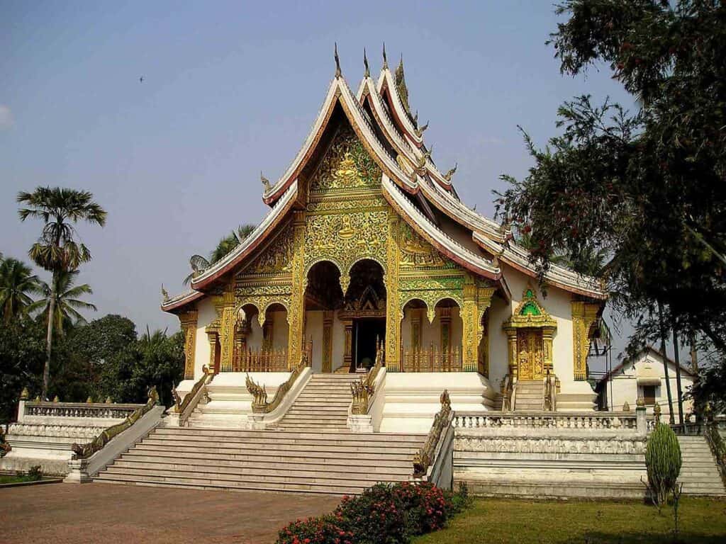 Traditional Thai temple with intricate gold details and tiered roof in a serene setting.