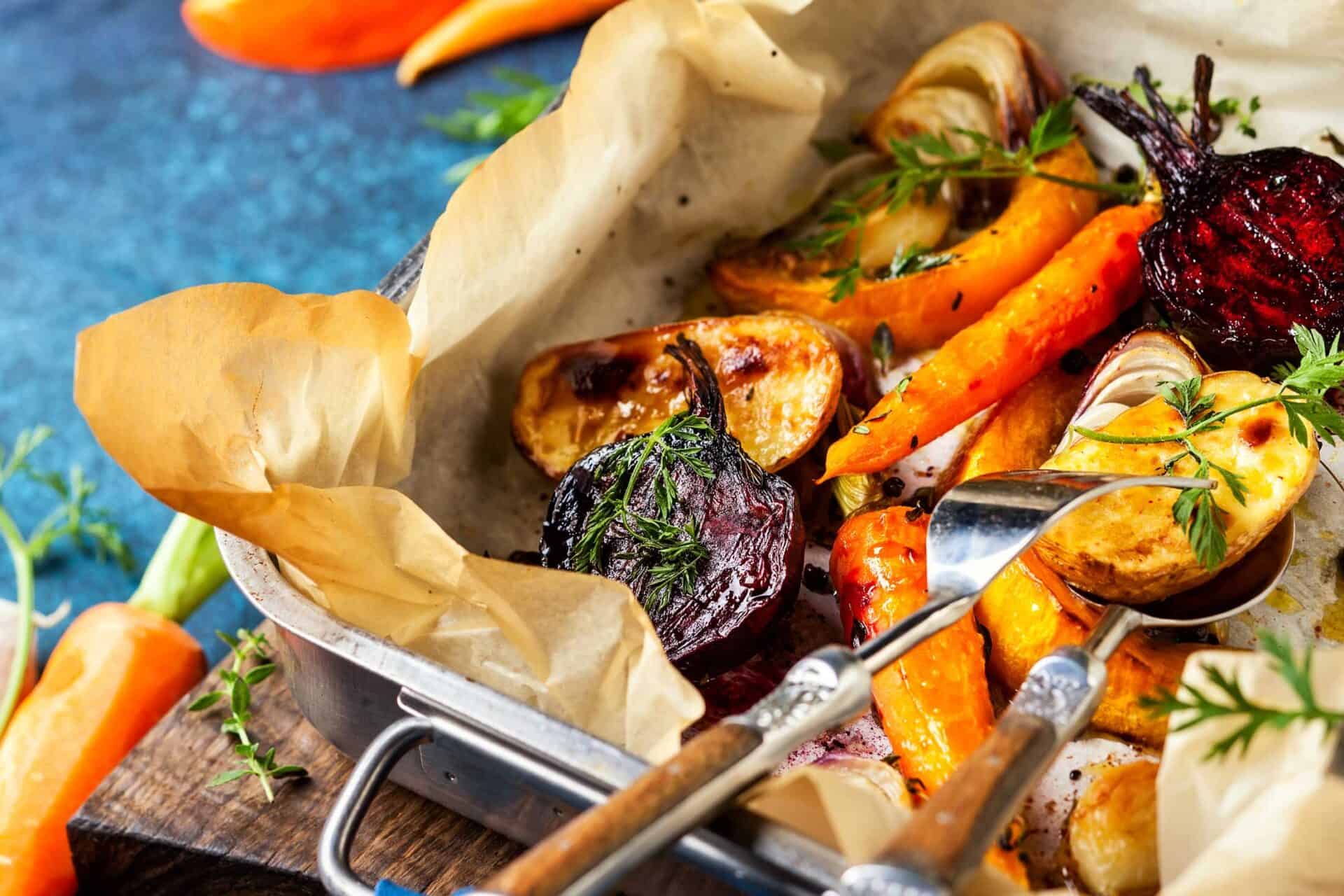 Roasted seasonal vegetables including carrots, beets, and potatoes, garnished with herbs.