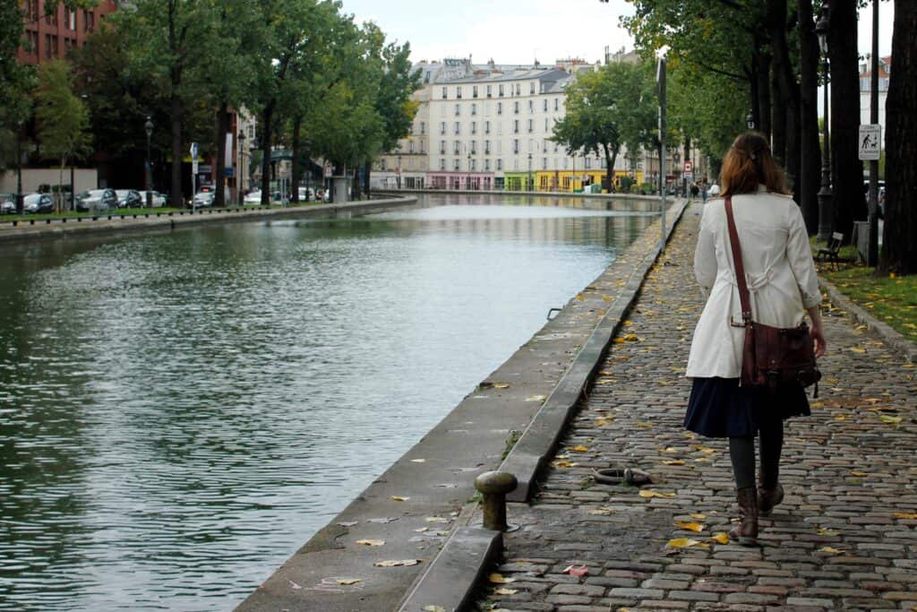 View of the canal near Mitte Hostel, Berlin, with a woman walking along the cobblestone path.