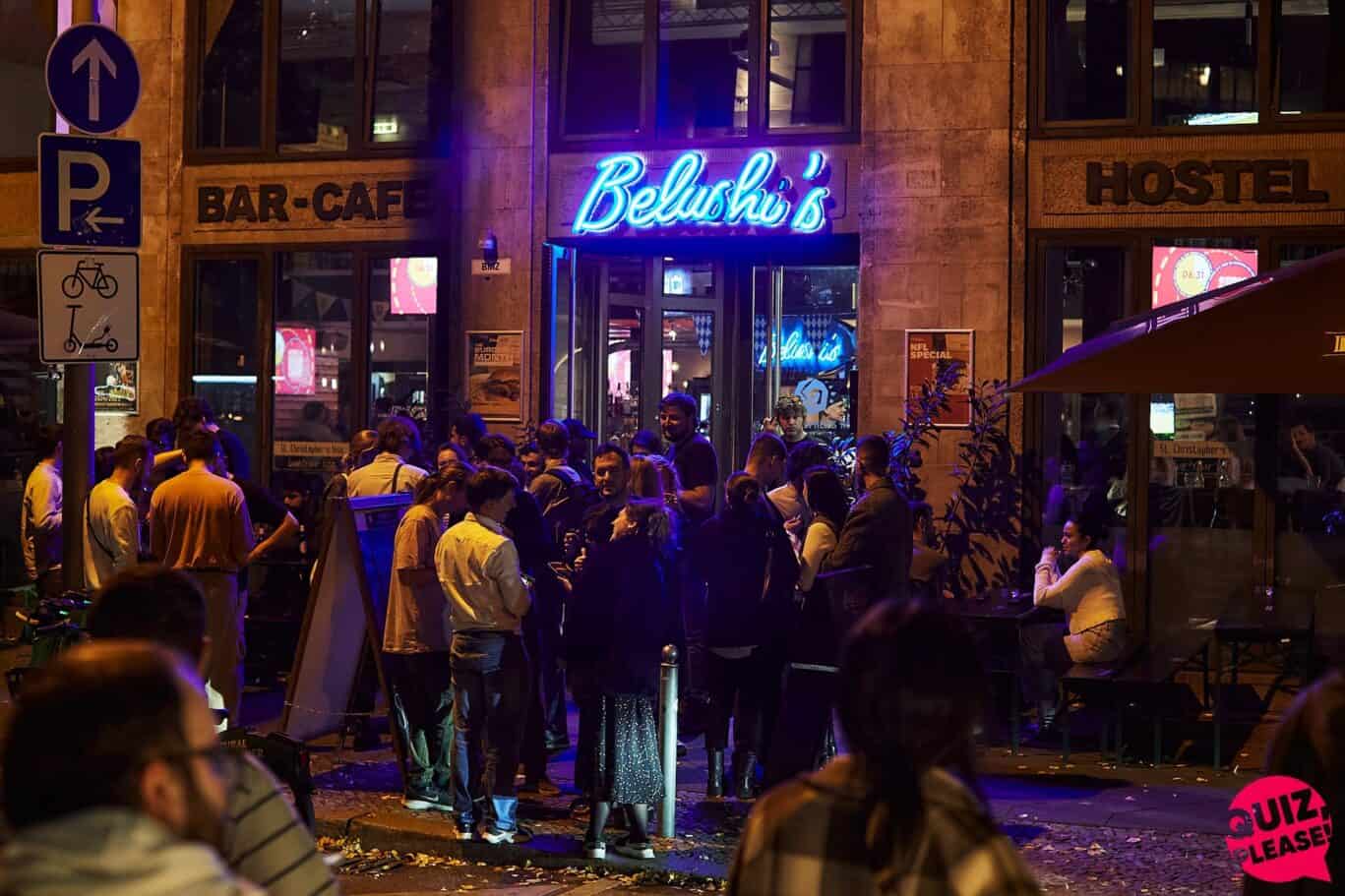 A busy social hostel bar with people gathered outside at night.