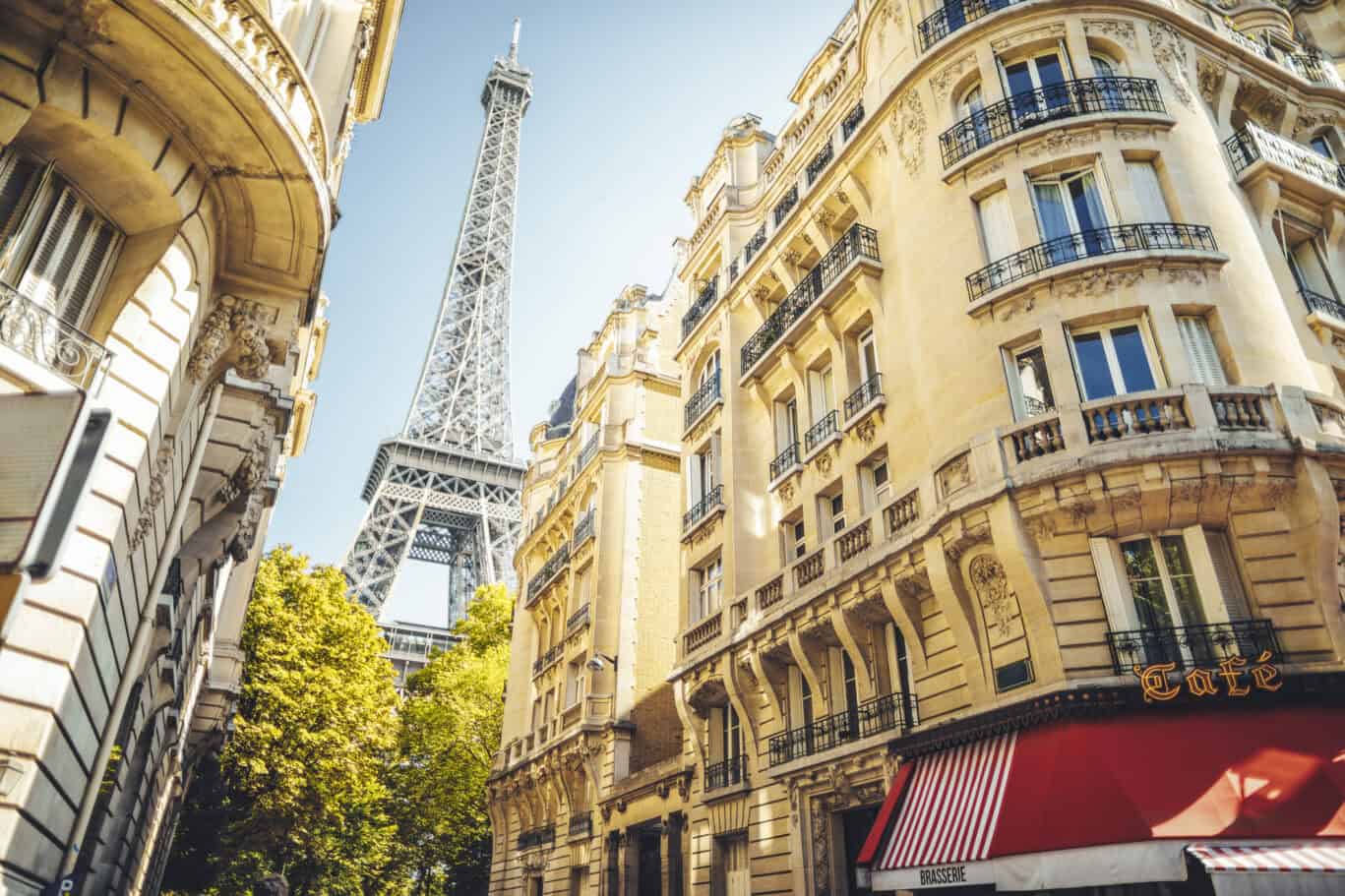 City street scene with classic Parisian buildings and the Eiffel Tower in the background.