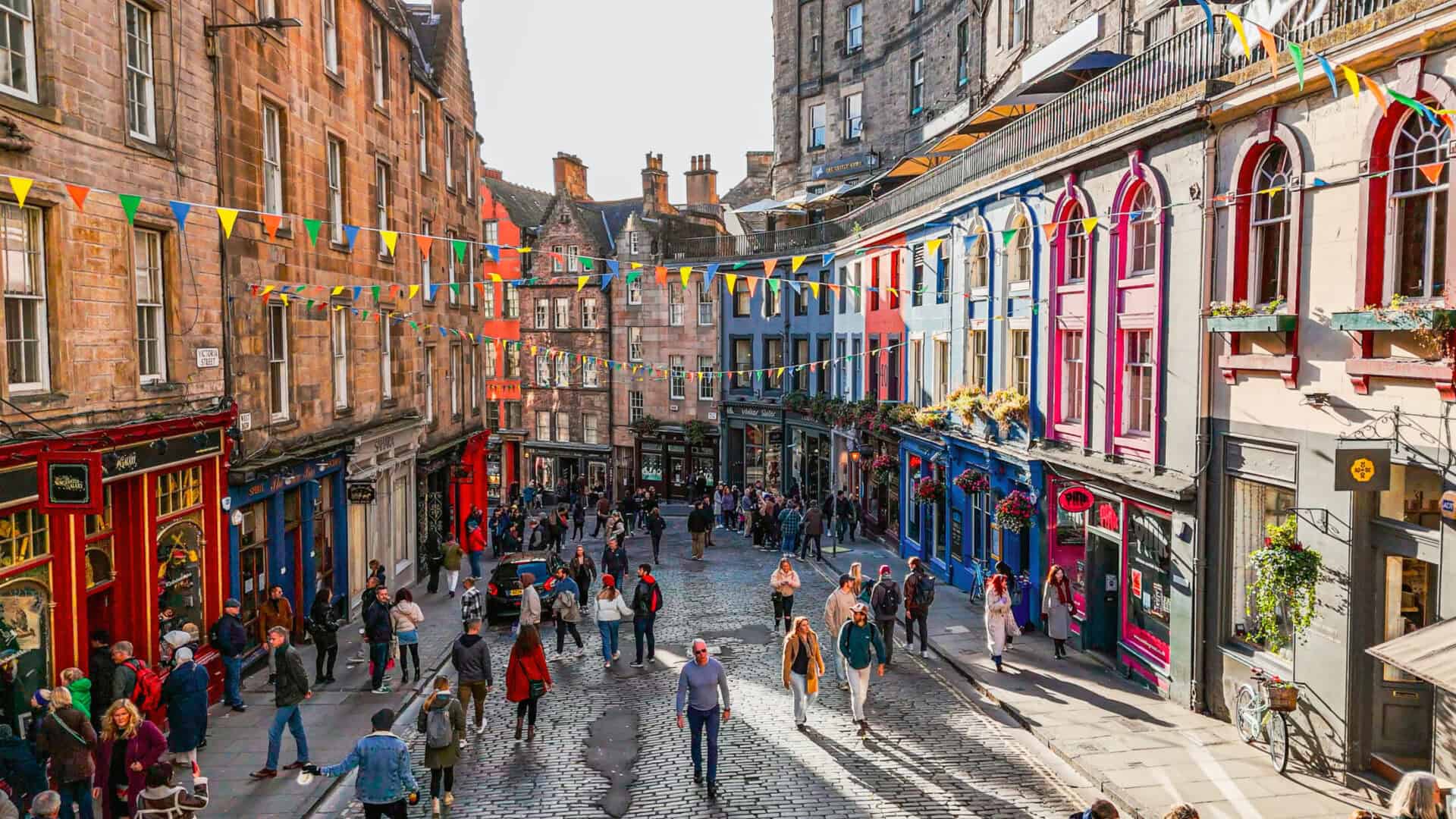 A lively city street with colourful buildings and pedestrians walking along the pavement.