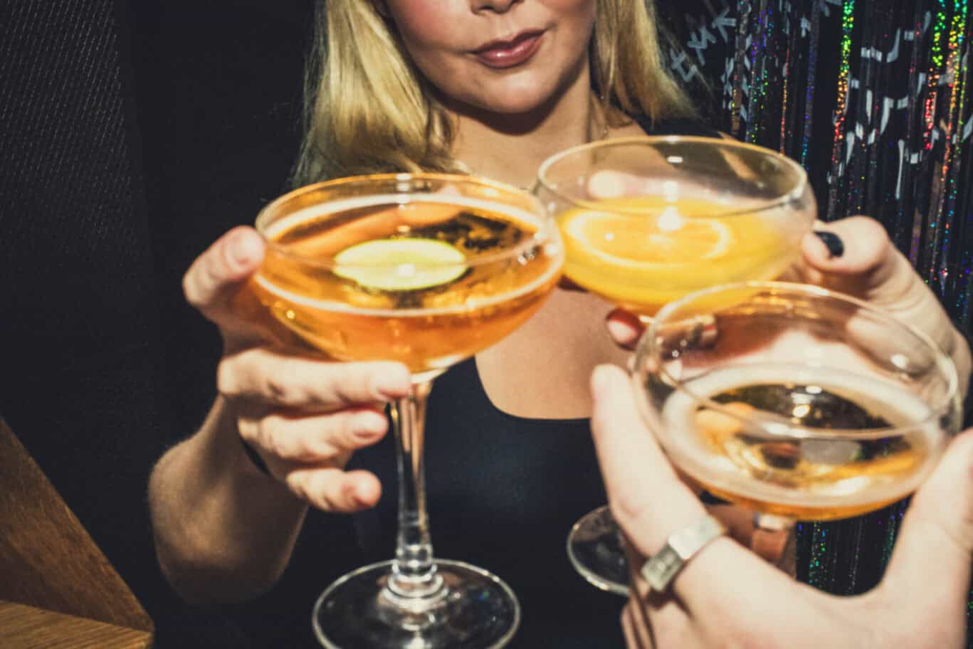 A social hostel bar scene with women holding cocktails in a lively setting.