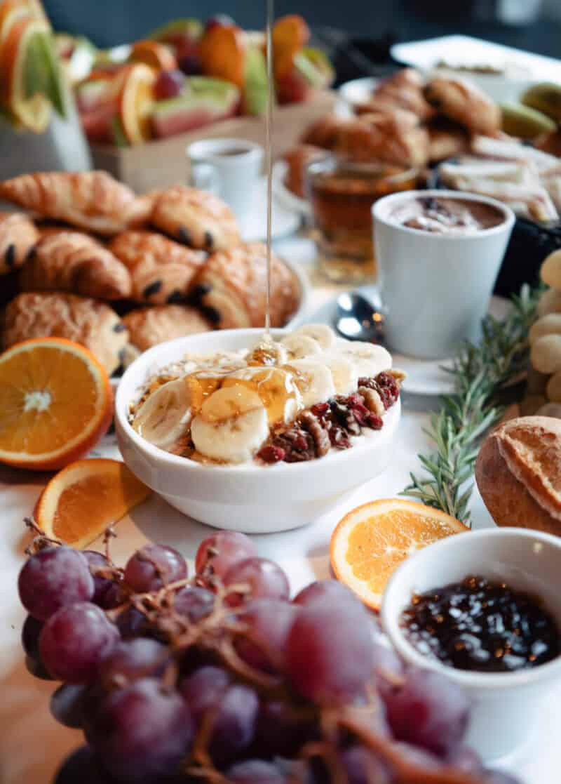 A breakfast spread with croissants, fruit, and coffee in a social hostel setting.