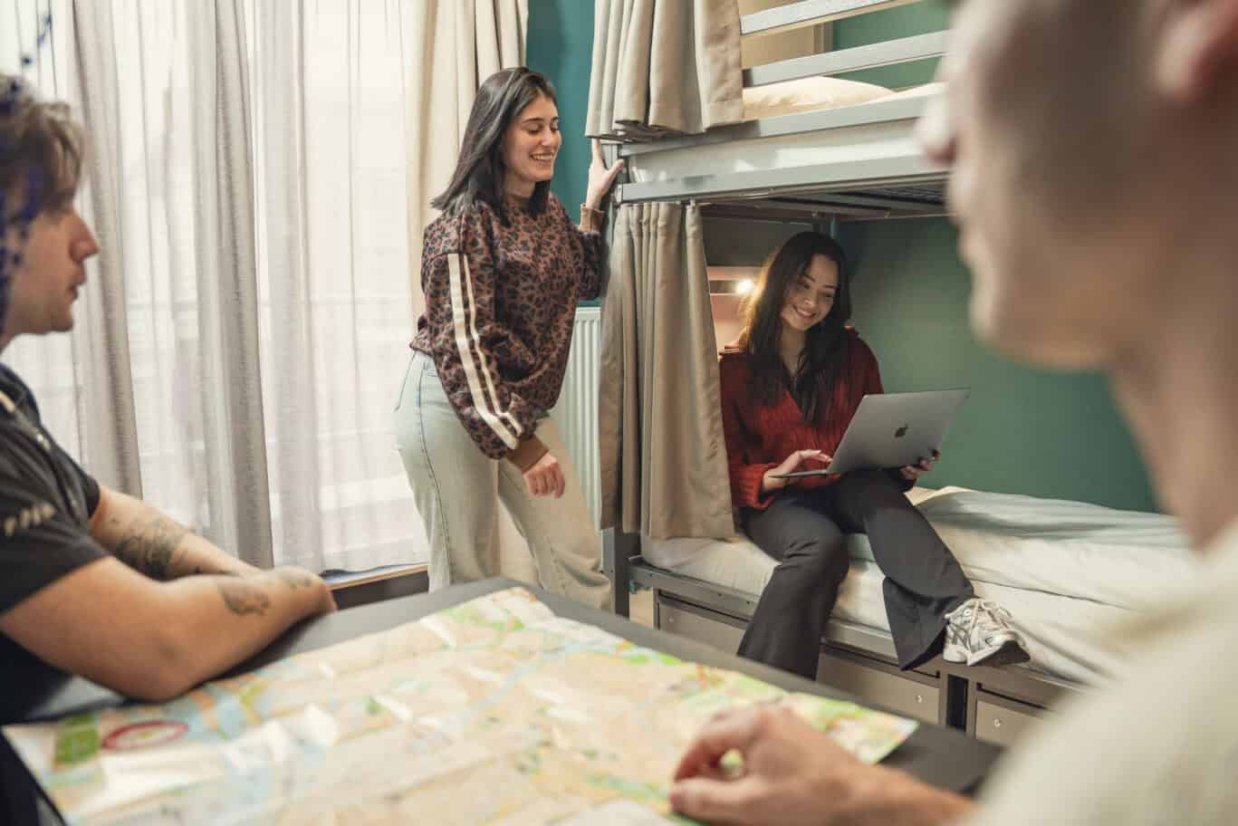 A dorm room in a St Christopher's Inn with a bunk bed and travellers relaxing.