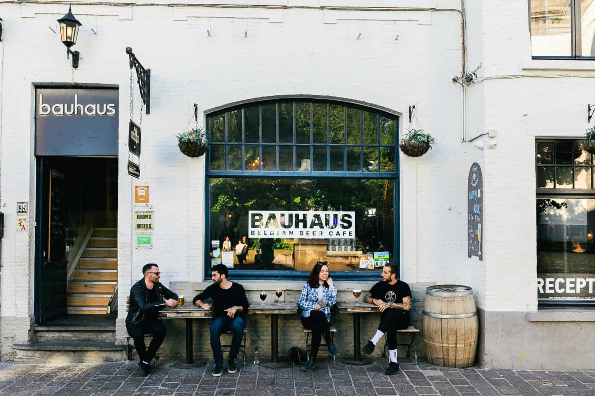 A social hostel bar with four people sitting outside on a bench.