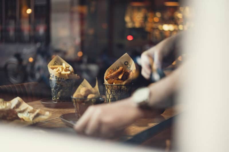 A social hostel bar with snacks and drinks on a wooden table.