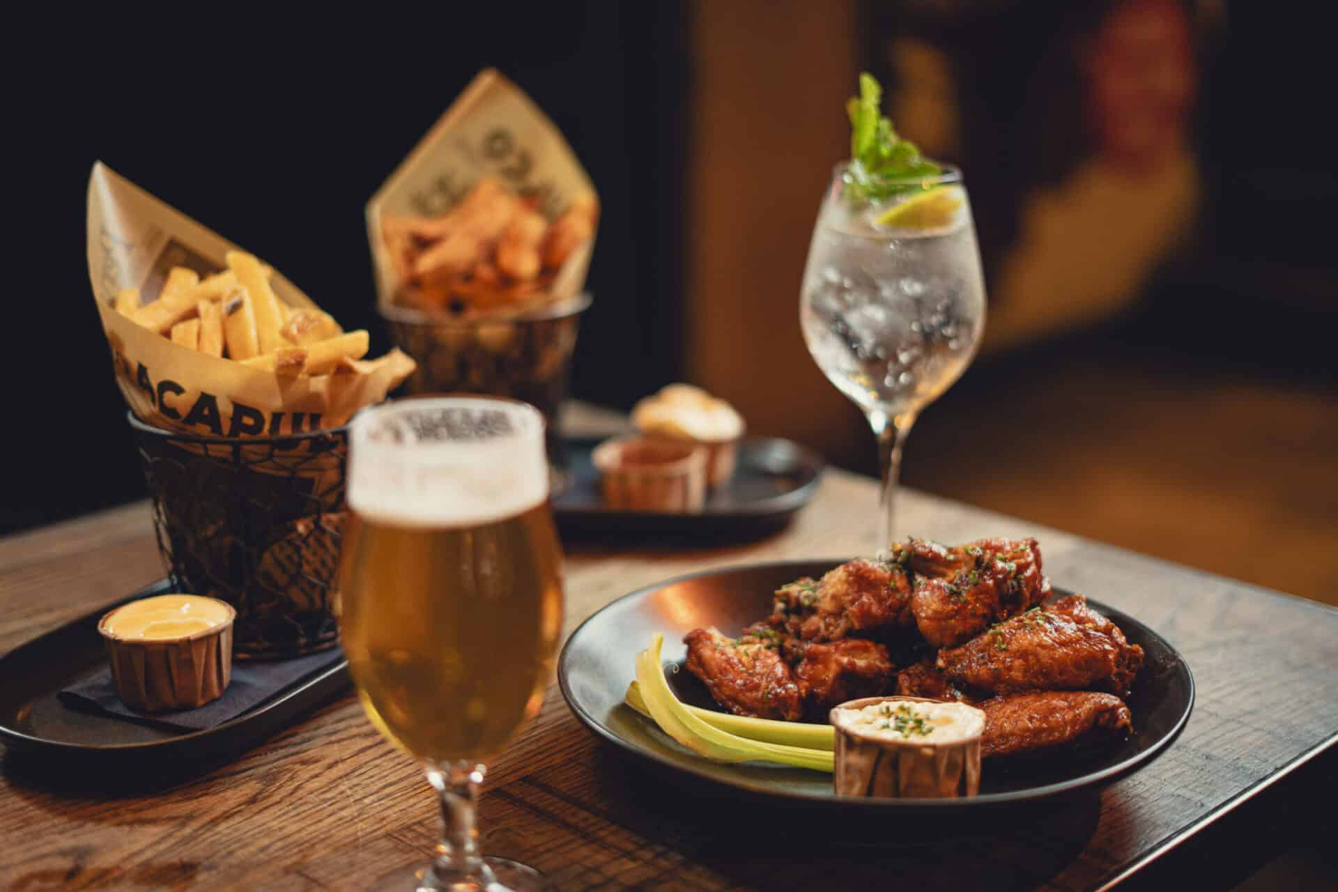 A social space with drinks and sharing plates in a hostel bar.