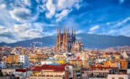 Cityscape with Sagrada Familia and colourful rooftops in the foreground.