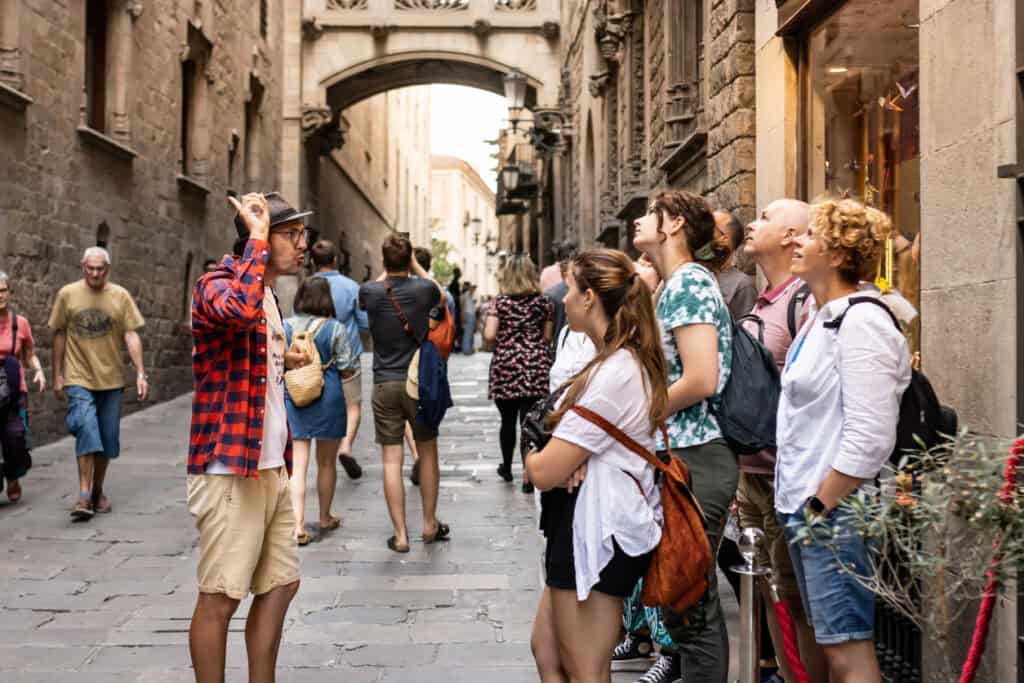 A group of travellers listening to a guide in a historic city street.