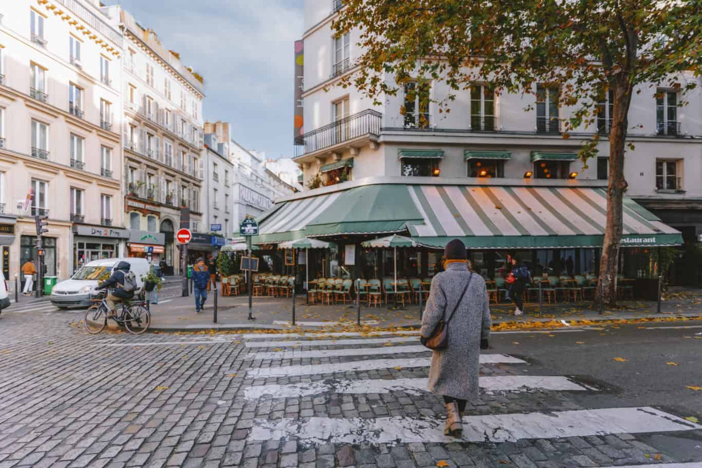 A street cafe with outdoor seating and pedestrians in a European city.