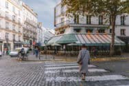 A street cafe with outdoor seating and pedestrians in a European city.