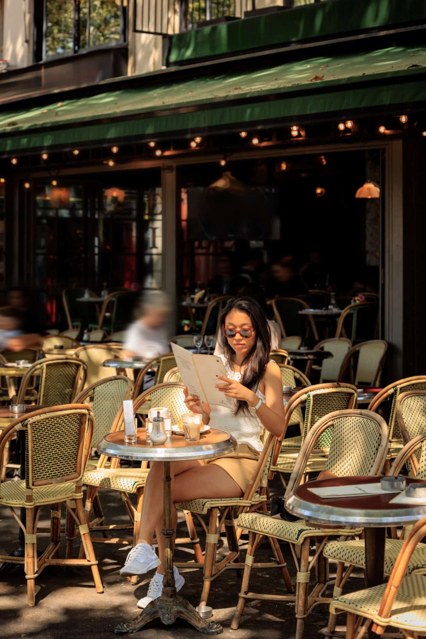 A woman reading a menu at an outdoor cafe in a social hostel.