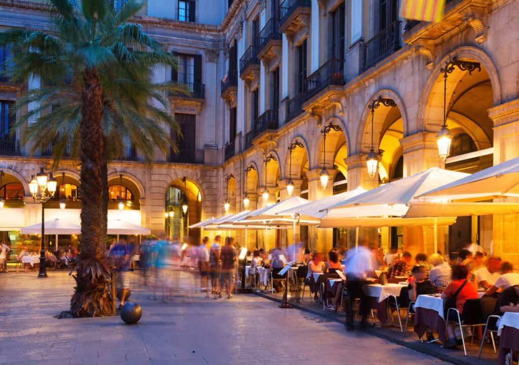 Outdoor dining area in a city centre with historic architecture and warm lighting.