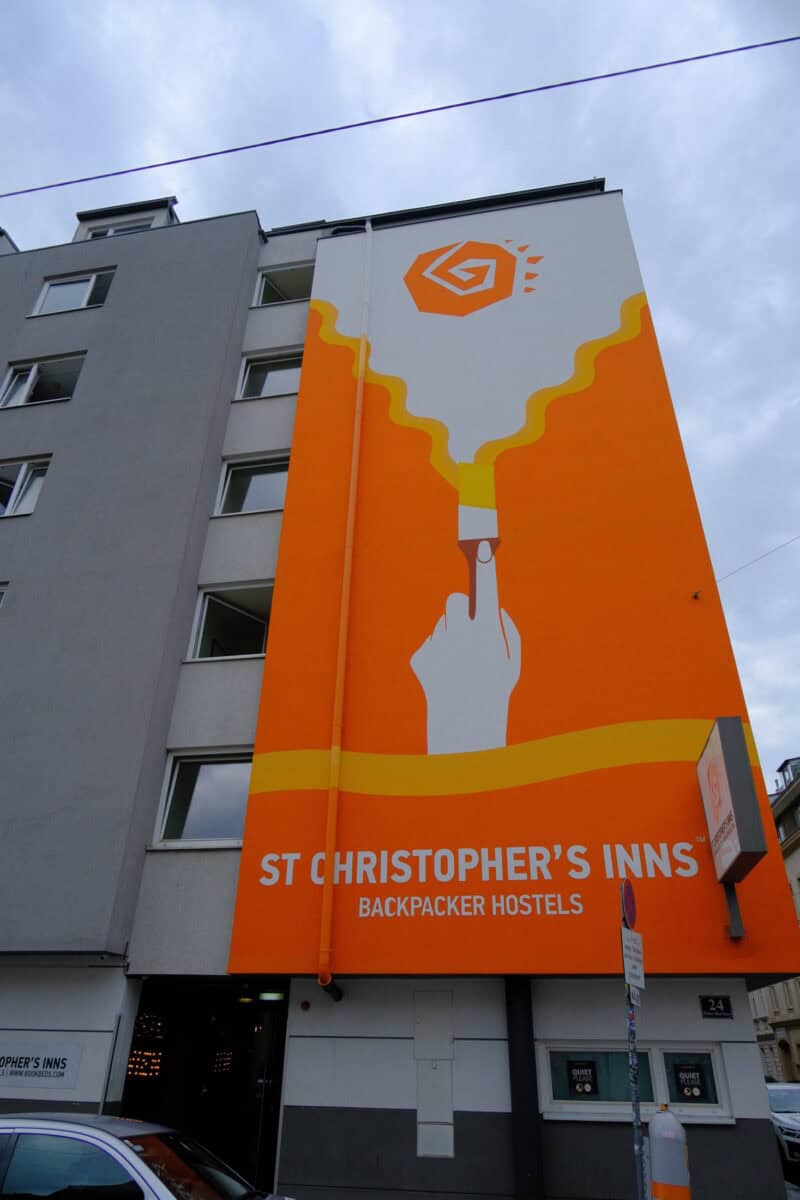 Large vertical sign for St Christopher's Inn backpacker hostel on building exterior.
