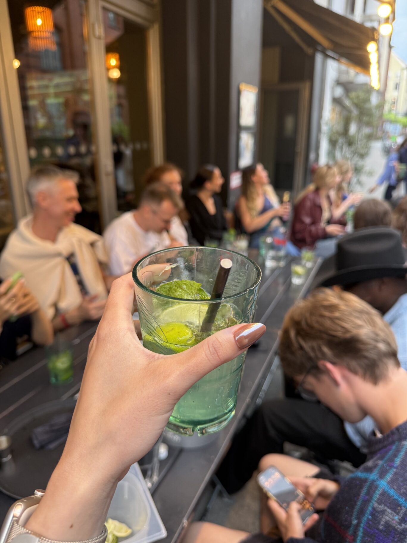 A social hostel bar with guests enjoying drinks and conversation outside.