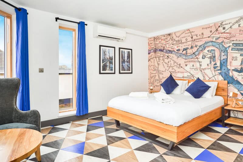 Comfortable hostel room with a large bed, vibrant blue curtains, and cityscape views in Berlin.
