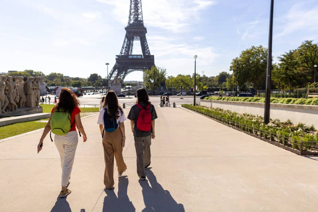 Eiffel Tower with three women tourists walking nearby, enjoying the view in Paris, France.