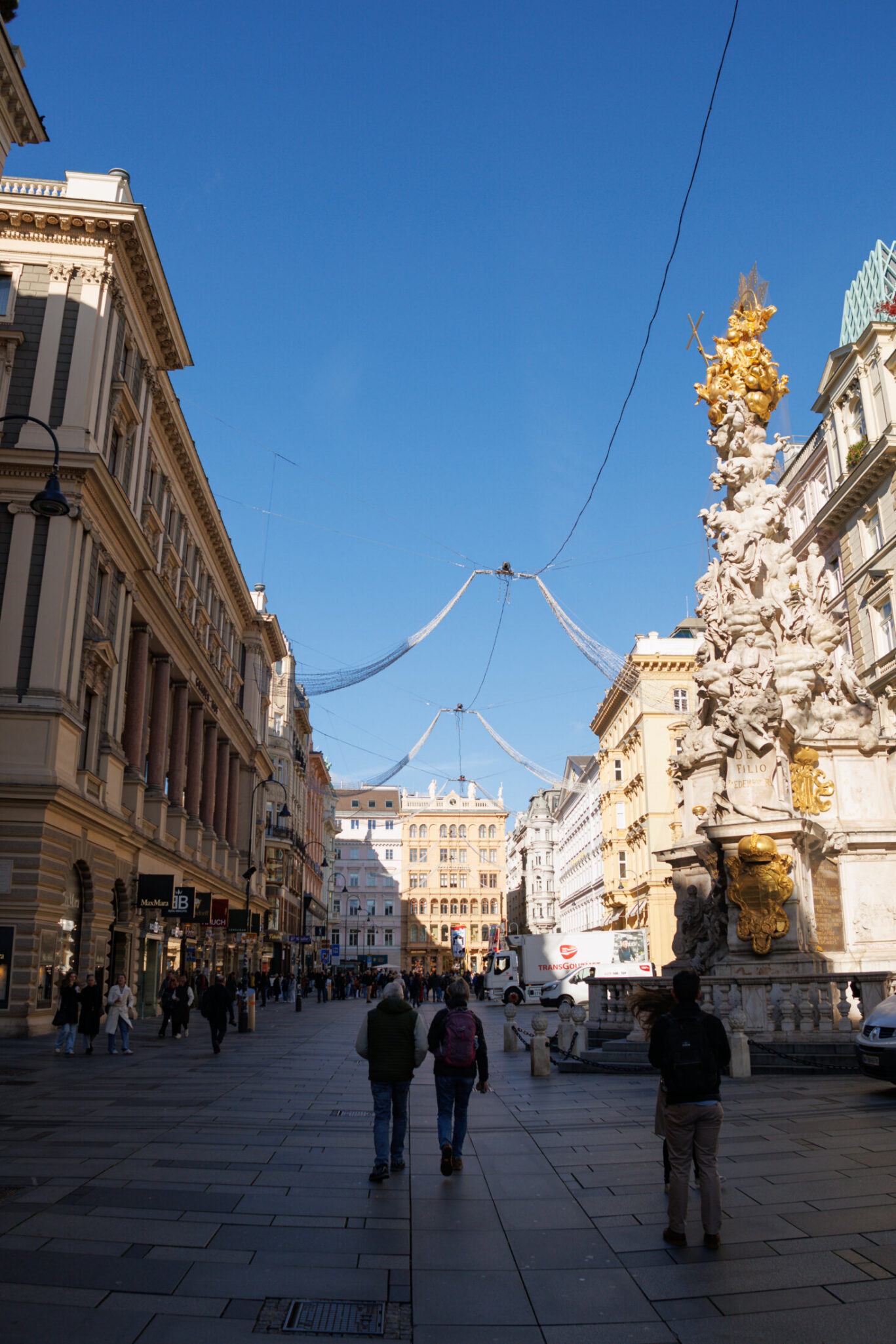 A busy city street with historic buildings and a large ornate fountain.