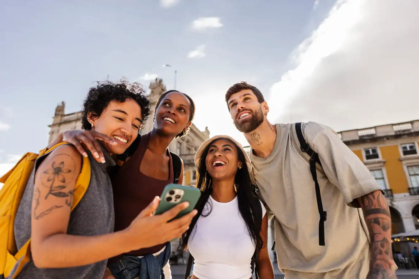 A group of diverse travellers smiling and taking a selfie outside a hostel.