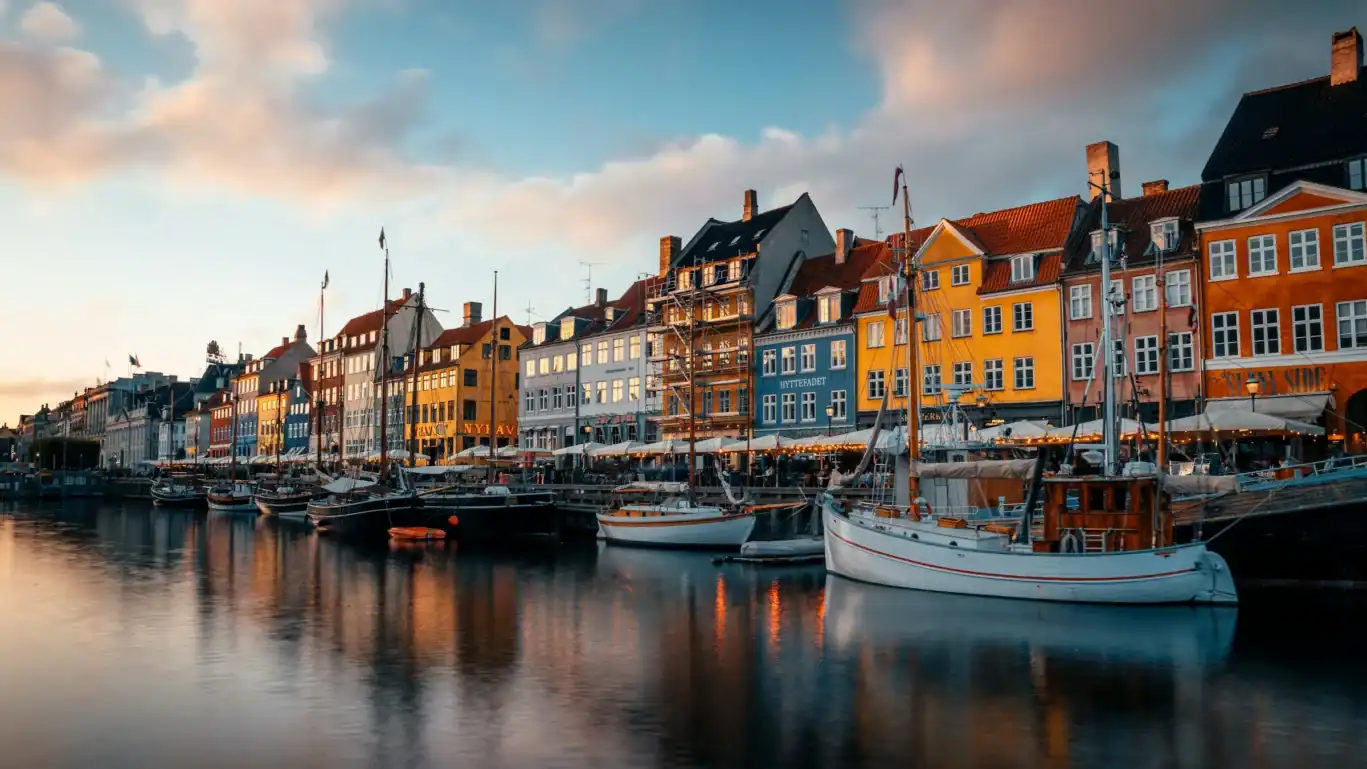 Colourful buildings along a harbour with boats and calm water.
