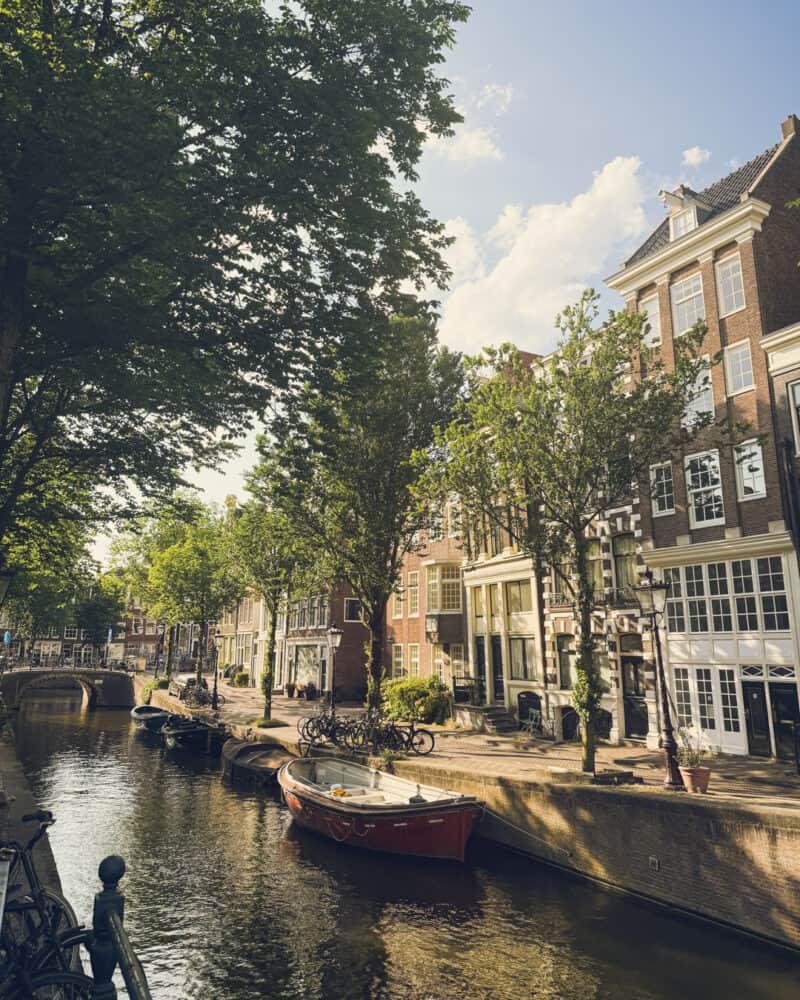 A canal with boats and historic buildings along a tree-lined street.