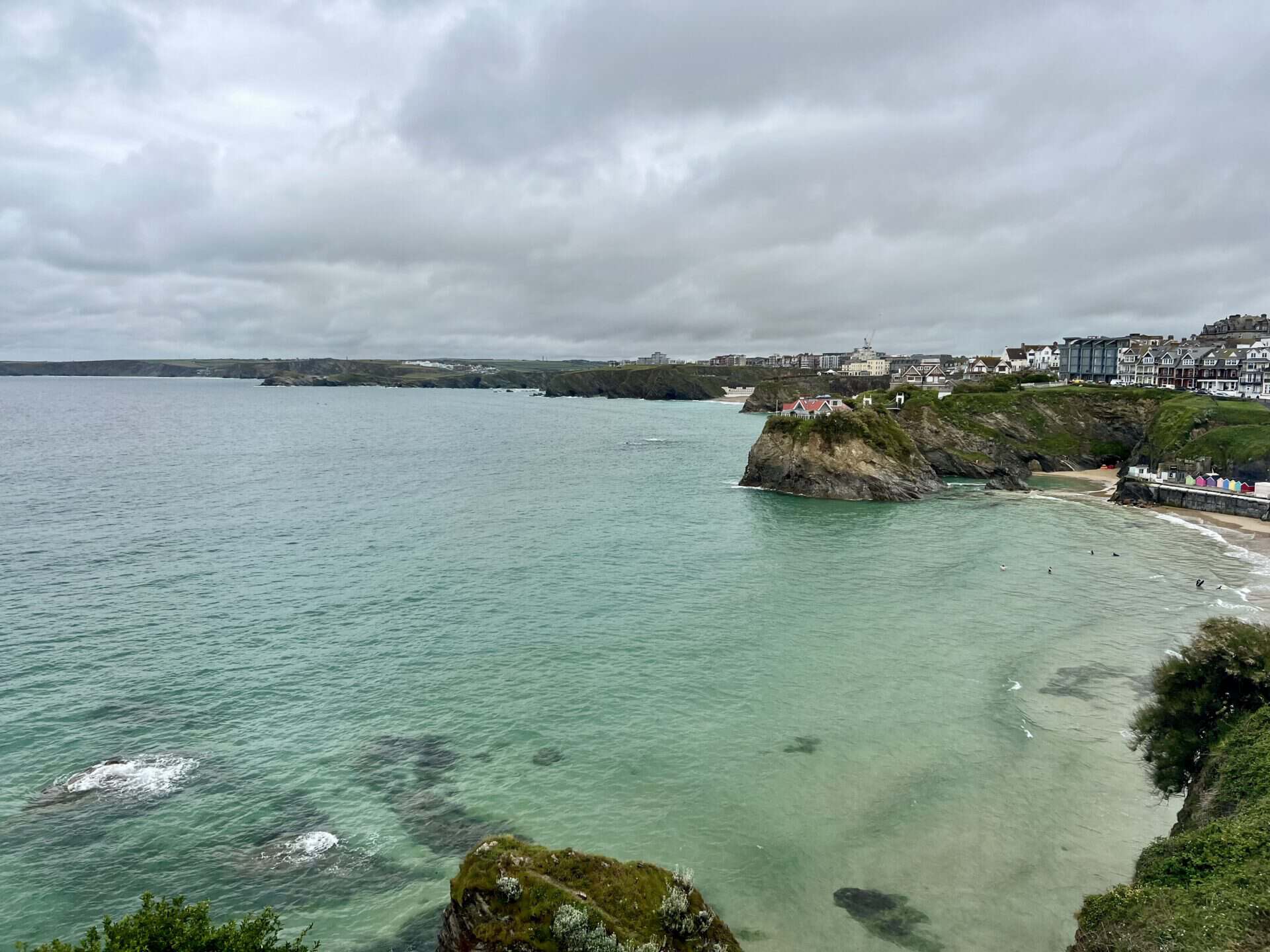 A scenic coastal view with cliffs, sea, and cloudy sky, seen from a hostel or social space.
