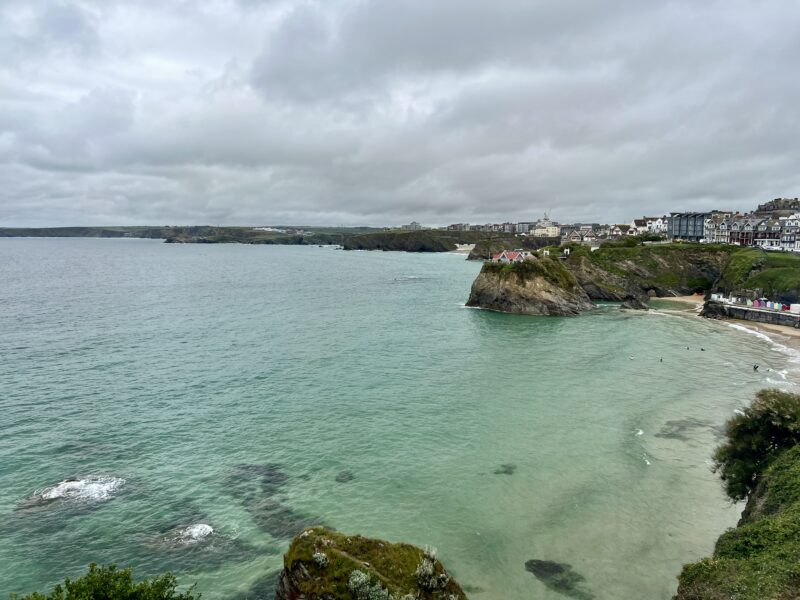 A scenic coastal view with cliffs, sea, and cloudy sky, seen from a hostel or social space.