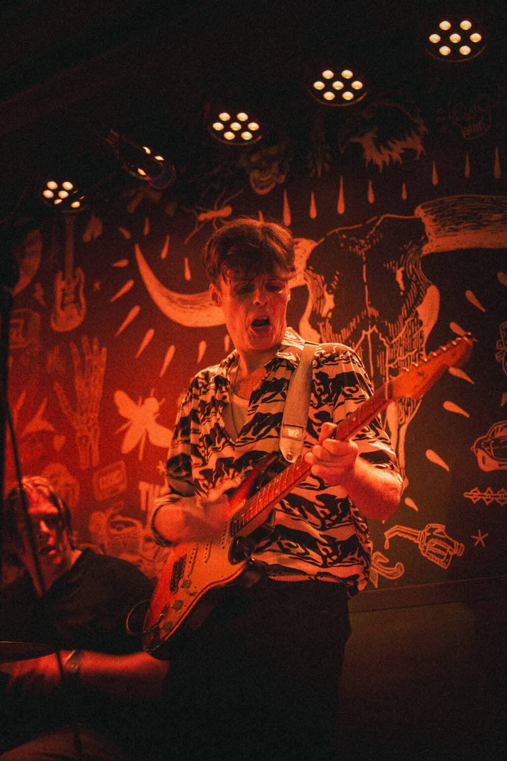 Young musician playing electric guitar on stage at Winston Hostel Amsterdam.