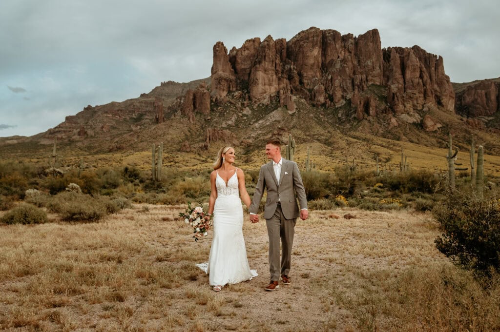 Couple walking hand in hand with saguaros during their Phoenix elopement, shot by Stratus Adventure Photography