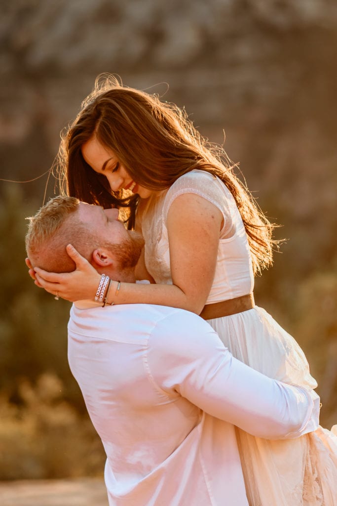 Bride gazing at her husband as he lifts her during sunset first dance