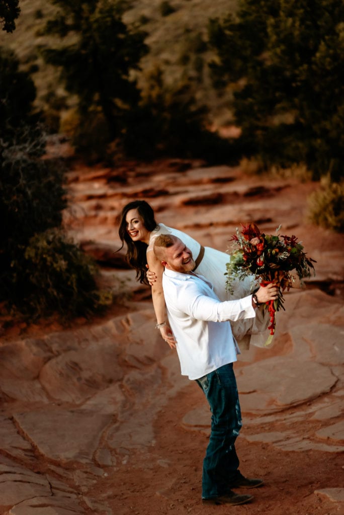 groom carrying bride over his shoulder laughing