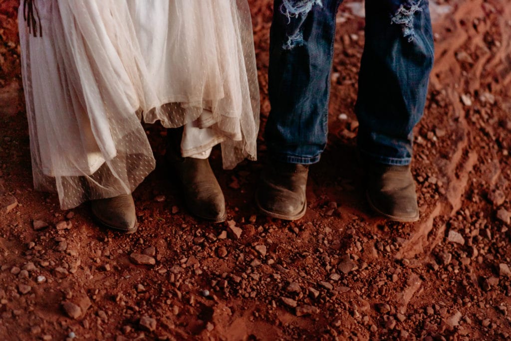 Cowboy boots and red rock dust Ombre on wedding dress during Merry Go Round Rock wedding