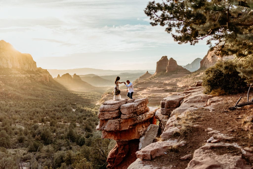 Bride and groom climbing up Merry go Round Rock pedestal on their Sedona Wedding