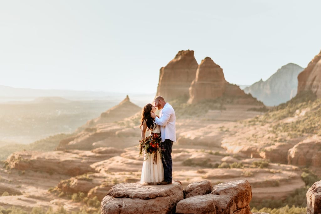 Groom gazing at his wife overlooking Sedona on a red rock ledge