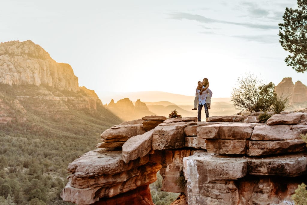 Bride piggy backs on Groom's back on a red rock ledge in Sedona