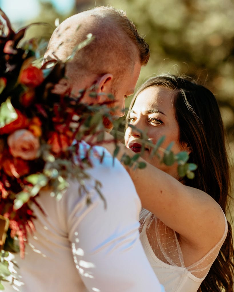 Bride gazing in to grooms eyes with a giant fall colored wildflower bouquet