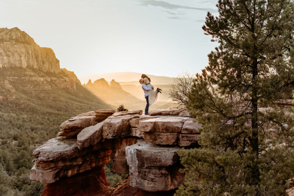 Groom lifting bride as the sun sets over Sedona