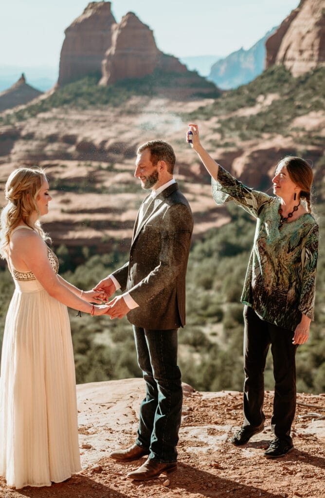 Officiant spritzing sage cleansing spray during elopement ceremony