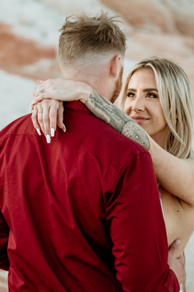 Cassie looks up at Nick with her hands draped over his neck