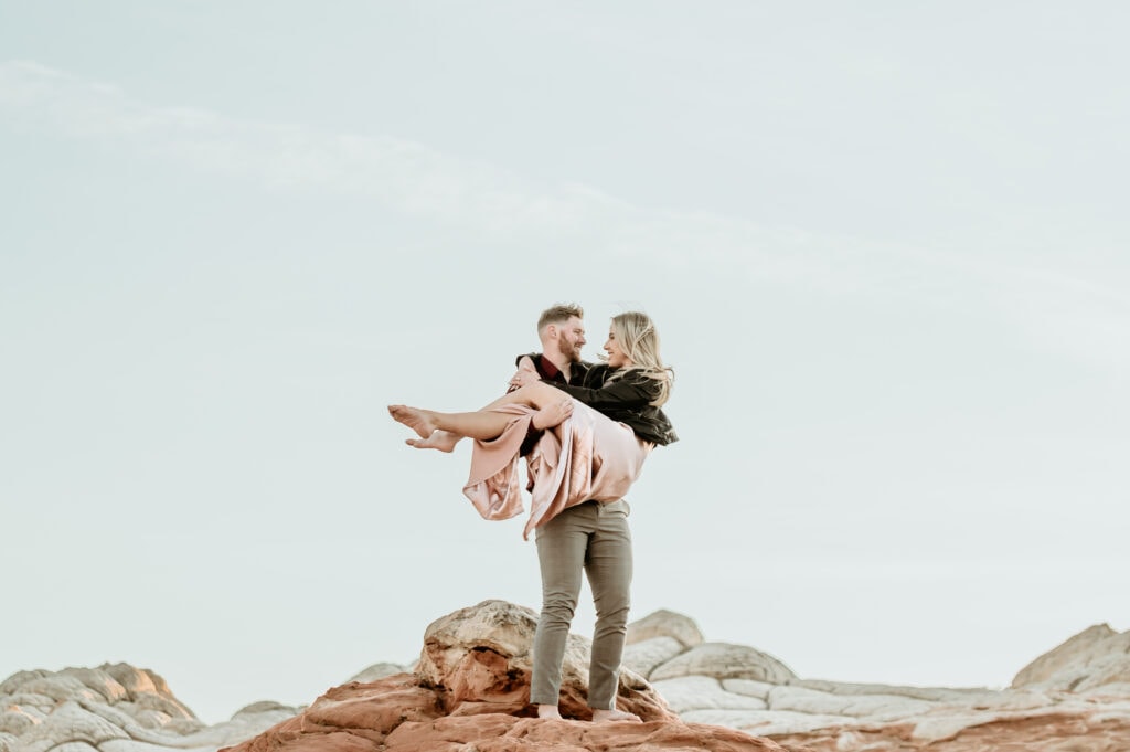 Nick lifts Cassie surrounded by waves of sandstone at the Vermillion Cliffs