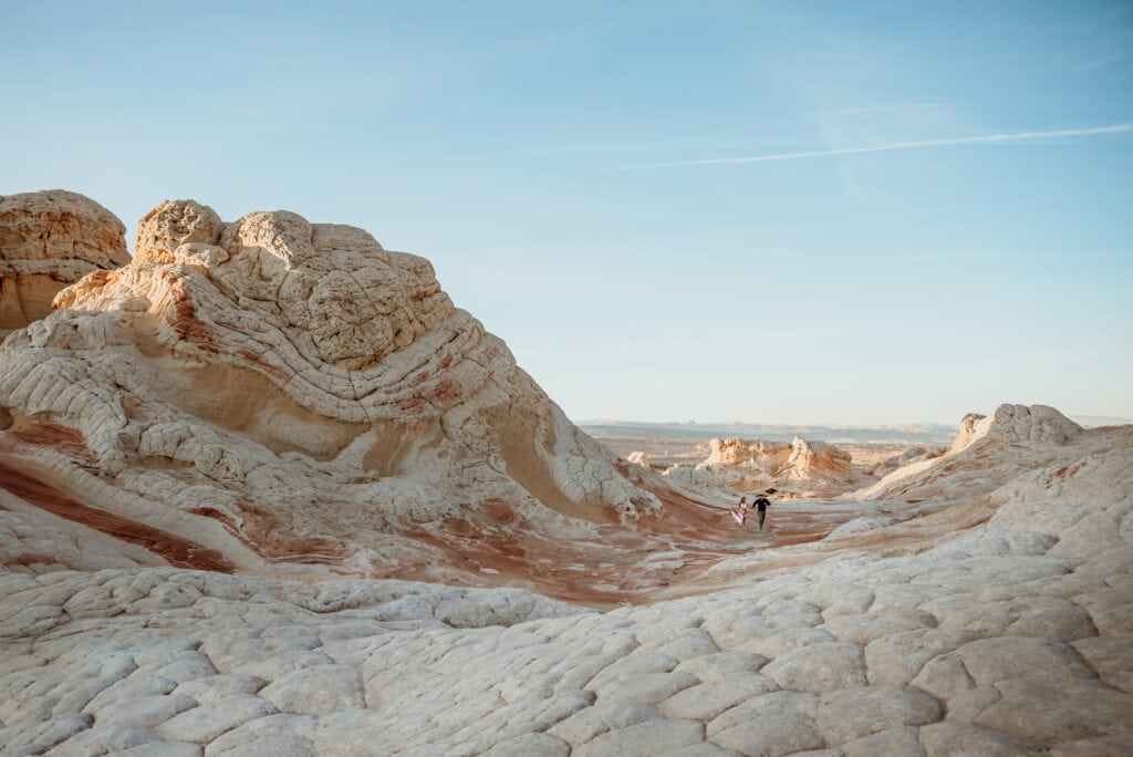 Cassie and Nick playfully running up the white rock formations of the Vermillion Cliffs